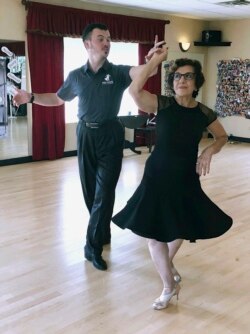 In this October 7, 2019, photo, dance instructor Ned Pavlovic, a native of Serbia, teaches his student Rouhy Yazdani, a native of Iran who now lives in Milford, Connecticut, some ballroom dance moves at the Fred Astaire Dance Studio in Orange, Connecticut