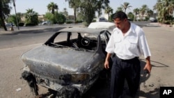 FILE - An Iraqi traffic policeman inspects a car destroyed by a Blackwater security detail in Nisoor Square in Baghdad, Iraq, Sept. 25, 2007.
