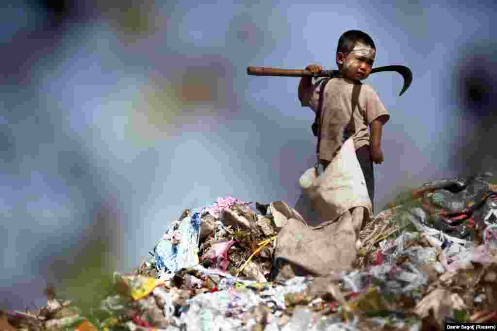 Tailândia: um menino imigrante ilegal birmanês recolhe plástico numa lixeira