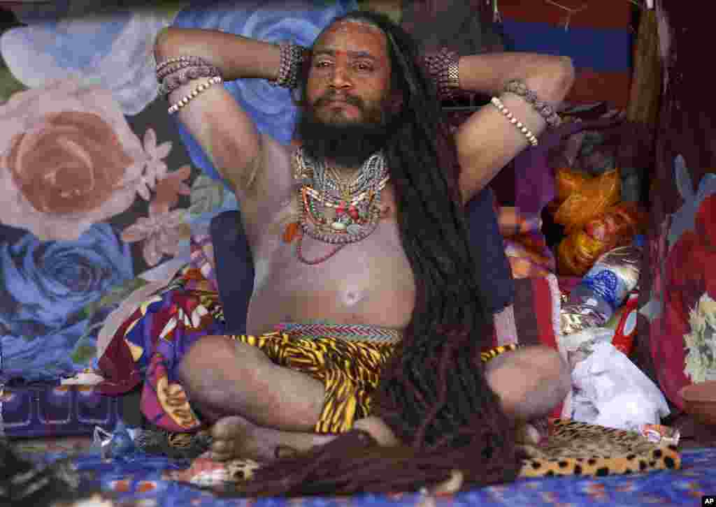 یک مرتاض هندی با موهای بلند در چادرش در هند به تصویر کشیده شده است.