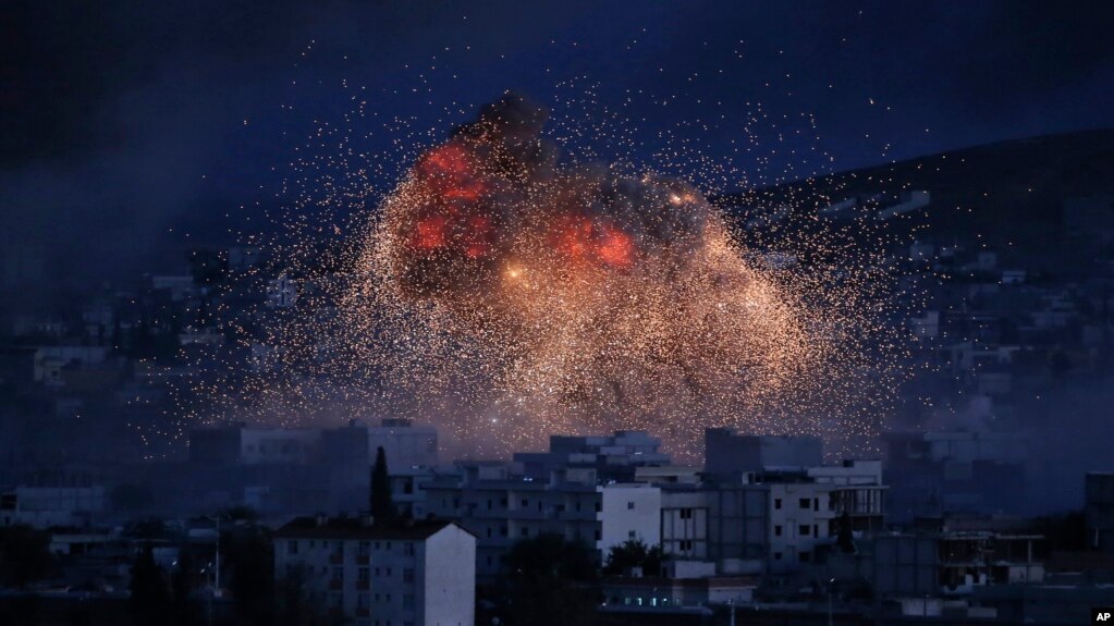 Cảnh tượng sau một trận không kích của liên minh do Mỹ dẫn đầu tại Kobani, Syria, tháng 10/2014. Quân đội Syria được đặt trong tình trạng báo động về khả năng một trận không kích của Mỹ có thể xảy ra sau khi chính quyền TT Bashar al-Assad bị cáo buộc tấn công bằng vũ khí hóa học vào thường dân.