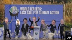 A replica of the COP26 summit's main UN negotiation stage, carrying activists dressed as world leaders, is half-sunk in the Clyde Canal during the COP26 summit in Glasgow, Scotland Tuesday Nov. 9, 2021.