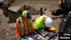 FILE - Field geologists conduct ground stability testing at a solar power plant development site located on a former coal mine in Hurley, western Virginia, May 11, 2021.