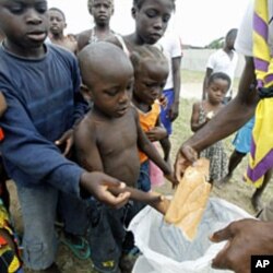 A man distributes bread to children at Abidjan's St. Ambrose church, a temporary refuge for people who fled from clashes between forces loyal to incumbent president Laurent Gbagbo and his rival Alassane Ouattara (File Photo)