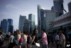 FILE - People walk across a main street in the financial district of Singapore.