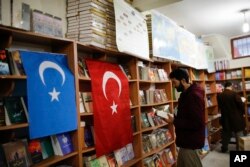 A man reads a book in a bookstore where flags which represents Turkey and "East Turkistan," the name Uighurs who oppose Chinese rule call their homeland, are hung in Istanbul's Zeytinburnu neighborhood, Dec. 14, 2017.