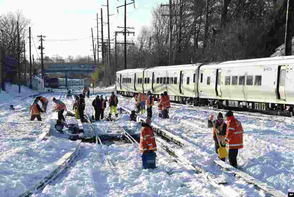 Workers clear the tracks of snow at the Port Washington branch of the Long Island Railroad, Monday, Jan. 25, 2016, outside of New York City.