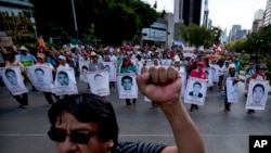 FILE -Relatives of the 43 missing students from the Isidro Burgos rural teachers college march holding pictures of their missing loved ones during a protest in Mexico City, July 26, 2015.