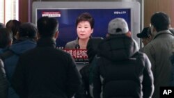 FILE - People watch a live broadcast of South Korean President Park Geun-hye addressing the nation at the Seoul Railway Station in Seoul, South Korea.