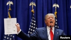 Tỉ phú Donald Trump cầm bảng báo cáo tài chính cho thấy tài sản của ông khi ông chính thức tuyên bố ra ứng cử tổng thống 2016