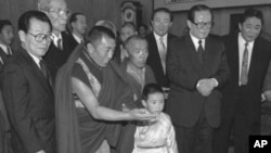 1996年1月12日，中方选择的六岁的11世班禅喇嘛向中国主席江泽民呈现给他的礼品。中国政协主席李瑞环在场。