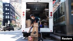 Seorang pekerja kantor pos AS (USPS) tampak menyortir barang dari truknya di wilayah Manhattan, Kota New York, pada 17 Agustus 2020. (Foto: Reuters/Carlo Allegri)