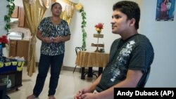 Ajuda Thapa, left, stands near her son, Jay Thapa, in their home in Burlington, Vermont. 