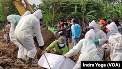 Petugas pemakaman menguburkan jenazah COVID-19 di TPU Rorotan, Jakarta Utara. 8 Juli 2021. (VOA/Indra Yoga)