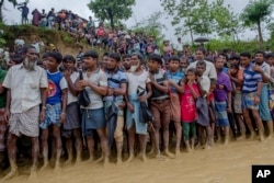 Rohingya Muslim men, who crossed over from Myanmar into Bangladesh, wait for their turn to collect food items distributed by aid agencies in Balukhali refugee camp, Bangladesh, Sept. 19, 2017.