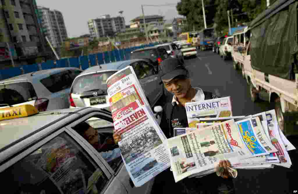 Seorang penjaja menjual surat kabar untuk pengendara yang berhenti di lalu lintas di Rangoon, Burma. Bagi warga Burma adalah hal baru surat kabar harian, yang dikelola pihak swasta (bukan pemerintah), dijajakan di jalanan. Sebelumnya pemerintah militer Burma melakukan monopoli atau kontrol atas pemberitaan/media. 