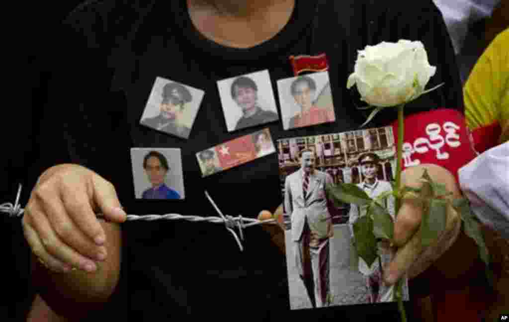 A woman holds a picture of Gen. Aung San and a white rose at a barricade leading to Martyrs' Mausoleum in Yangon, Myanmar, Sunday, July 19, 2015. Hundreds of people gathered to pay respect at the tomb of Myanmar's Independence hero and opposition leader A