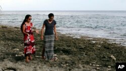 FILE - Global warming activist Milan Loeak, left, and poet Kathy Jetnil-Kijiner walk along the shore at low tide in Majuro Atoll in the Marshall Islands, Nov. 8, 2015. 