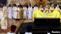 FILE - Orthodox Patriarch Alexiy II (L) leads a mourning ceremony at the coffin of Empress Maria Fyodorovna, the wife of Tsar Alexander III and mother of Russia's last monarch, Nicholas II, in St. Isaac's cathedral in St. Petersburg, Sept. 28, 2006. Russian investigators say they plan to exhume the remains of Tsar Alexander III at the request of the Orthodox Church to authenticate the remains of his son, the murdered last tsar, and his slain children. 