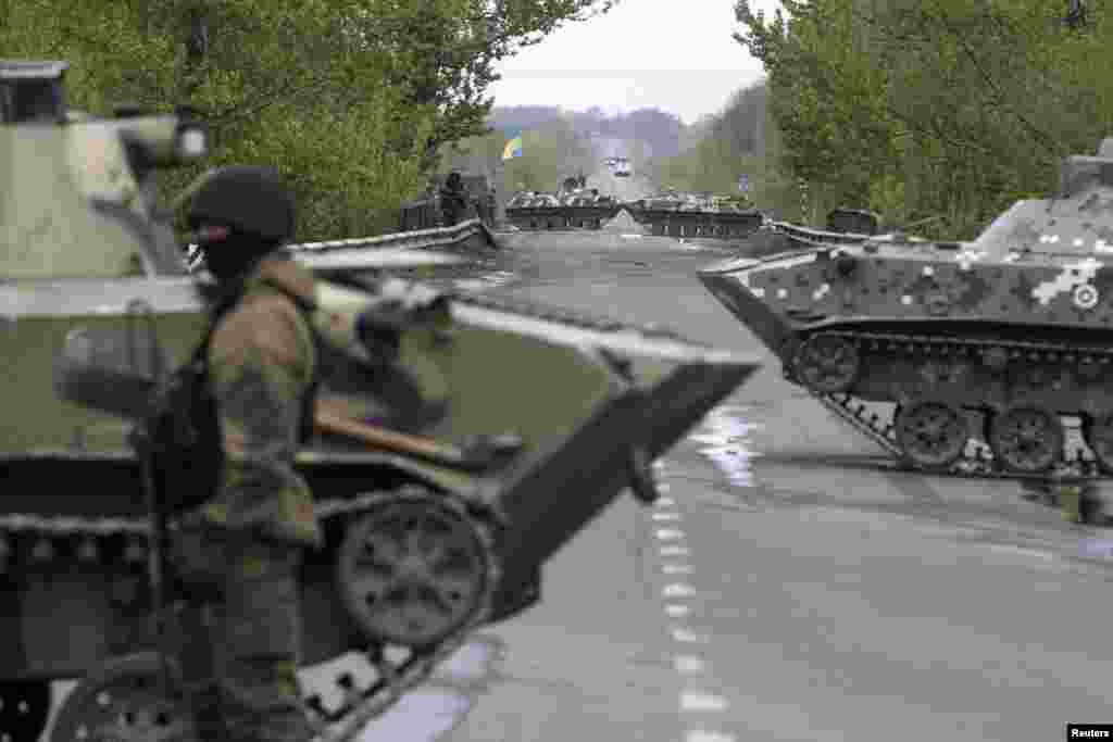 A Ukrainian soldier stands guard in front of armored personnel carriers at a check point near the village of Malinivka, southeast of Slaviansk, in eastern Ukraine.