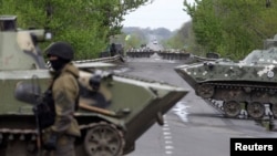 A Ukrainian soldier stands guard in front of armored personnel carriers at a check point near the village of Malynivka, southeast of Slovyansk, in eastern Ukraine, April 29, 2014