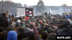 Prajurit Belarusia mengendalikan situasi sementara para migran antre untuk mendapatkan bantuan kemanusiaan di perbatasan Belarusia-Polandia dekat Grodno, Belarus, Jumat, 12 November 2021. (Ramil Nasibulin/BelTA pool photo via AP)