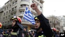 FILE - Firefighters chant slogans in front of a Greek flag during a protest in central Athens, Feb. 8, 2016