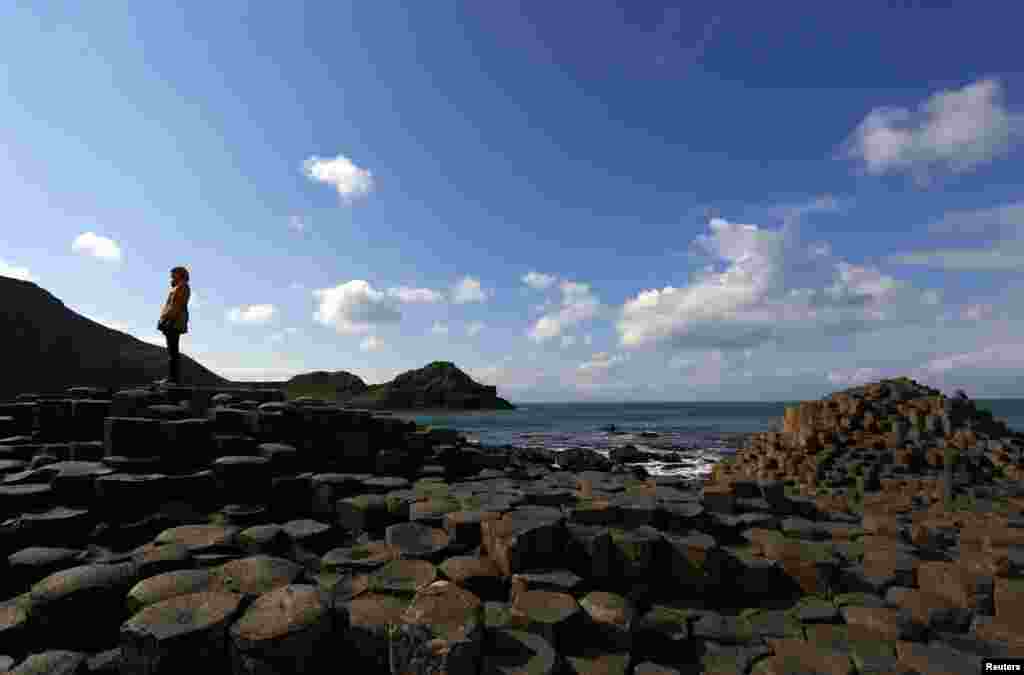 A woman stands on the rocks at the Giant&#39;s Causeway situated on the north coast of Northern Ireland.