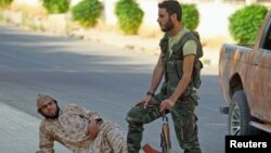 Fighters from a coalition of rebel groups called "Jaish al Fateh" rest with their weapons in the Hama countryside, Syria, July 29, 2015.