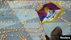 Seorang pengunjuk rasa mengibarkan bendera dalam demonstrasi menentang penertiban China terhadap unjuk rasa di di Tibet, di Lapangan Sergel, Stockholm, 21 Maret 2008. Lilin-lilin membentuk kata-kata “Tibet Merdeka.”