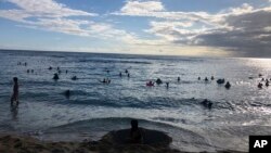 In this photo taken May 13, 2020 in Honolulu, people are in the water at a Waikiki beach.