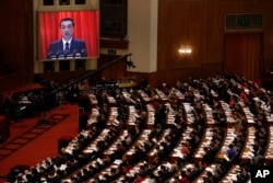 Chinese Premier Li Keqiang is shown on a large screen as he delivers a work report at the opening session of the annual National People's Congress at the Great Hall of the People in Beijing, March 5, 2018.