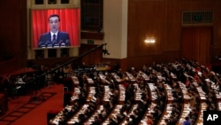 Chinese Premier Li Keqiang is shown on a large screen as he delivers a work report at the opening session of the annual National People's Congress at the Great Hall of the People in Beijing, March 5, 2018.
