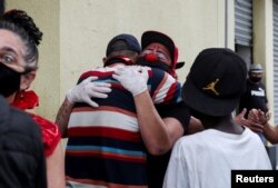 Flavio Falcone hugs a man as Andrea Macera, talks to other men as they check on people in an area known as "cracolandia" in the historic center of Sao Paulo, Brazil, February 9, 2021. REUTERS/Amanda Perobelli