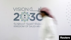 A man walks past the logo of Vision 2030 after a news conference, in Jeddah, Saudi Arabia, June 7, 2016.