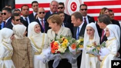 Kanselir Jerman Angela Merkel (tengah) dan Presiden Dewan Uni Eropa Donald Tusk (kanan) berbicara pada gadis-gadis muda di kamp pengungsi Nizip di provinsi Gaziantep, Turki (23/4). (AP/Lefteris Pitarakis)