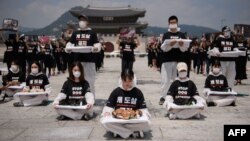 Para aktivis perlindungan hak-hak binatang 'Animal Liberation Wave' dan 'Last Chance for Animals' menunjukkan bangkai anak anjing yang diambil dari peternakan anjing dalam demo menentang perdagangan daging anjing di Seoul, Korea Selatan, 17 Juli 2018. (Foto: AFP)