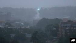 An electric transformer explodes in the distance as heavy rains and wind from Hurricane Michael blanket the Florida State University campus, Oct. 10, 2018, in Tallahassee, Fla.