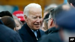 FILE - Former vice president Joe Biden,who just announced his candidacy for the 2020 elections, talks with officials after speaking at a rally in support of striking workers in Boston, April 18, 2019.