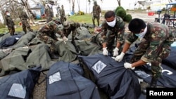 Soldiers zip up body bags after families have identified their relatives who perished during super typhoon Haiyan in Tacloban city, central Philippines, Nov. 13, 2013.