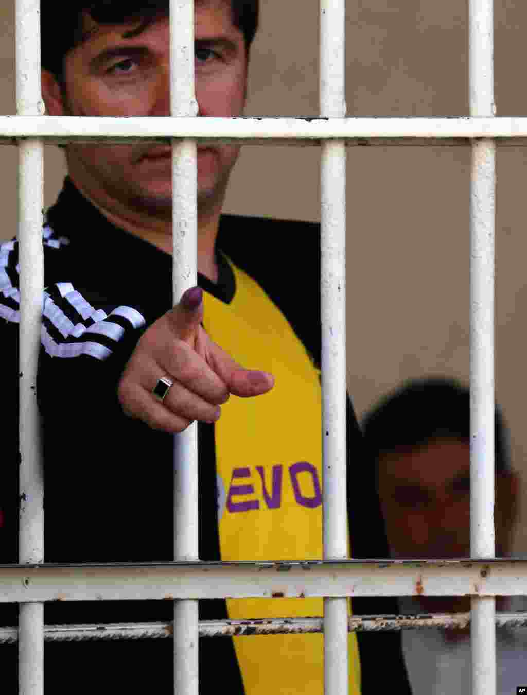 A detainee shows his inked finger after casting a vote at the polling center inside a prison in Irbil, April 28, 2014.
