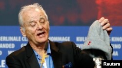 Actor Bill Murray shows the Silver Bear for Best Director award for Wes Anderson for movie "Isle of Dogs" at the news conference after the awards ceremony at the 68th Berlinale International Film Festival in Berlin, Germany, Feb. 24, 2018.