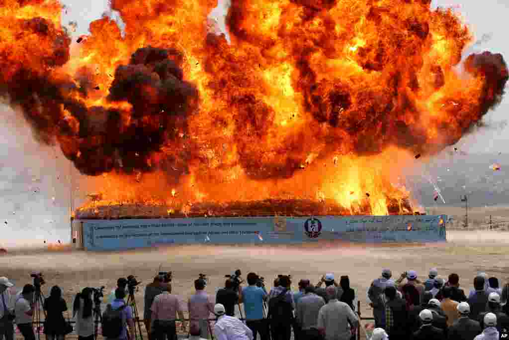 People look at a pile of seized narcotics is set fire during a ceremony commemorating International Day Against Drug Abuse and Illicit Trafficking in Tehran, Iran. 