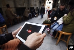 FILE - A man tries to get connected to the YouTube web site with his tablet at a cafe in Istanbul, March 27, 2014.