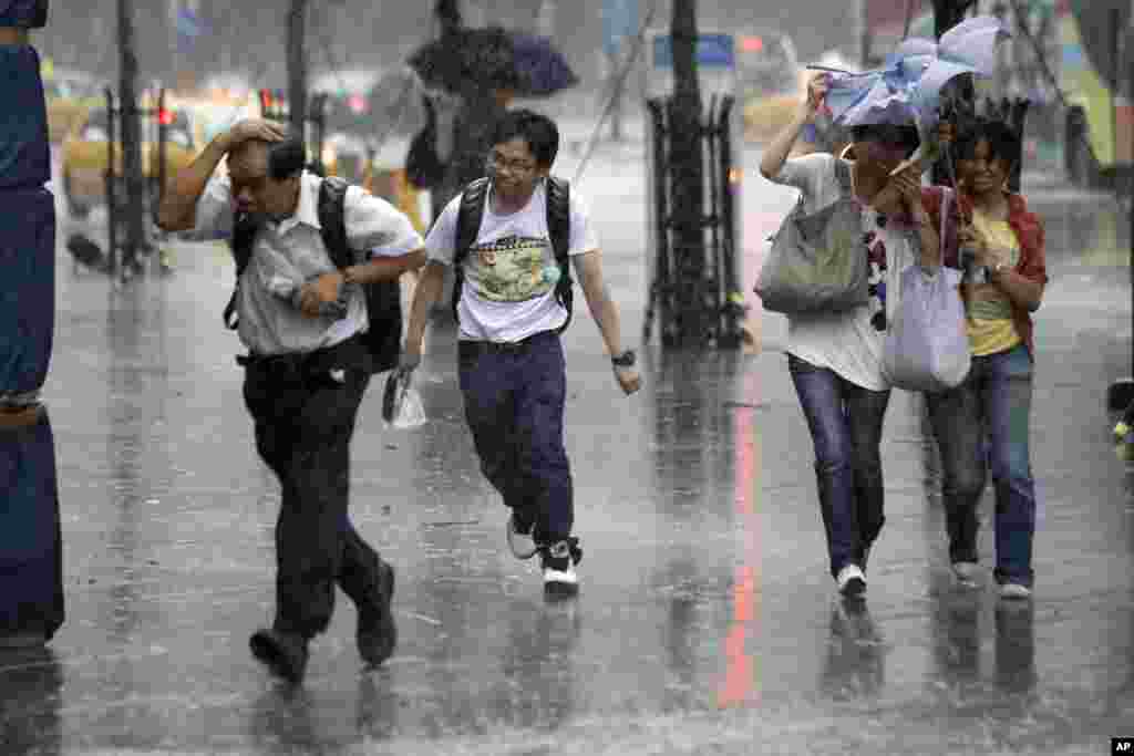 Tourists brave winds and rain from the approaching Typhoon Saola in Taipei, Taiwan, August 1, 2012. 