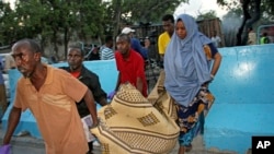 Somalis carry away the dead body of a person who was killed when a car bomb detonated in Mogadishu, Somalia, May 24, 2017.