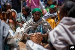 FILE - Mwanamke wa Kiethopia akichukua ngano baada ya kugawiwa na Jumuiya ya Misaada ya Relief Society ya Tigray. (AP Photo/Ben Curtis)