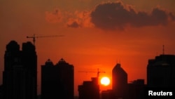 FILE - The sun sets behind buildings under construction in Guangzhou, Guangdong province.