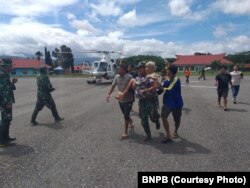 Anggota TNI AD dibantu warga menggotong salah satu korban banjir yang dievakuasi menggunakan helikopter BNPB di Konawe utara, Sulawesi Tenggara, 6 Juni 2019. (Foto: Humas BNPB)