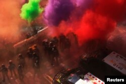 Separatist protesters throw colored powder toward Mossos d'Esquadra police officers in Barcelona, Spain, Sept. 29, 2018, as they protest against a demonstration in support of the Spanish police units who took part in the operation to prevent an independence referendum in Catalonia on Oct. 1, 2017.